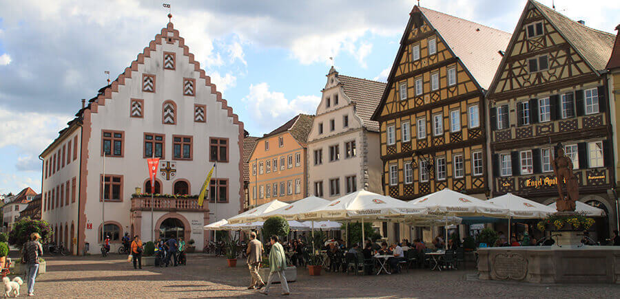 Der belebte Marktplatz Bad Mergentheims mit altem Rathaus, Fachwerkhäusern und Restaurants.