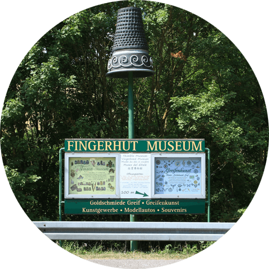 Schild vor dem Eingang des Fingerhutmuseum in Creglingen mit übergroßem Fingerhut